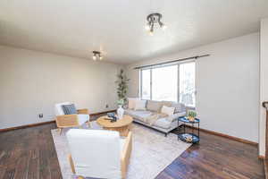 Living area with dark wood-type flooring and a textured ceiling
