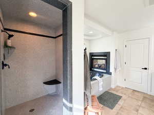 Bathroom featuring recessed lighting, a shower, a multi sided fireplace, and light tile patterned flooring