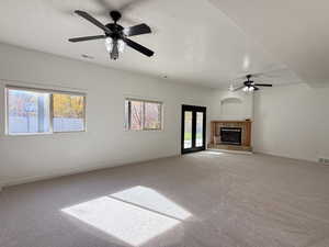 Unfurnished living room with a textured ceiling, a ceiling fan, carpet flooring, and a tile fireplace