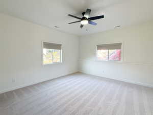 Unfurnished room with light carpet, plenty of natural light, and ceiling fan