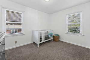 Bedroom featuring dark colored carpet and a crib