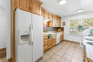 Kitchen with white appliances, light countertops, light tile patterned floors, and tasteful backsplash