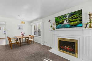 Dining space with carpet flooring, a fireplace with flush hearth, a textured ceiling, and plenty of natural light