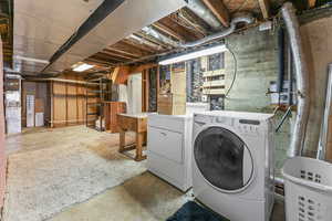 Washroom with concrete flooring and washer and clothes dryer
