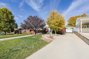 Obstructed view of property featuring an outdoor structure, a front yard, concrete driveway, and brick siding
