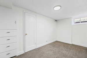 Below grade area with a textured ceiling and carpet flooring