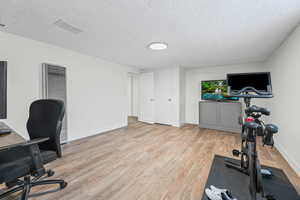 Office with light wood-style floors, a heating unit, and a textured ceiling