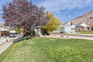 Obstructed view of property featuring a front lawn, a mountain view, and brick siding