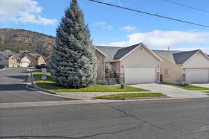 View of front of house with stucco siding, stone siding, driveway, a residential view, and an attached garage