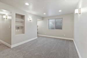 Carpeted empty room with built in features, recessed lighting, and a textured ceiling