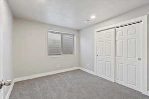 Unfurnished bedroom with carpet flooring, a textured ceiling, and a closet