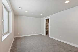 Empty room with light carpet, recessed lighting, and a textured ceiling