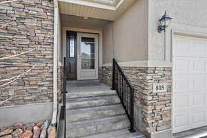Doorway to property with stone siding, stucco siding, and covered porch