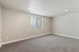 Empty room with light carpet, a textured ceiling, and recessed lighting