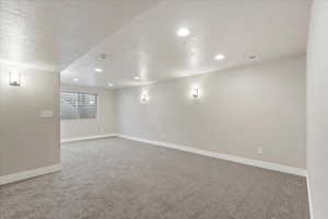 Empty room featuring a textured ceiling, light carpet, and recessed lighting