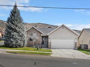 View of front facade with driveway, stone siding, stucco siding, an attached garage, and a residential view