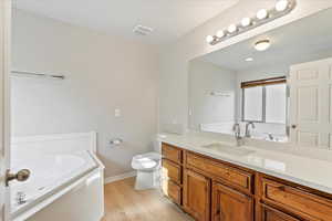 Bathroom with a bath, vanity, and light wood-type flooring
