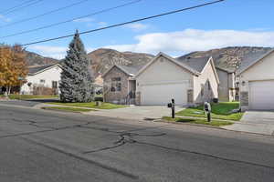 Ranch-style house with stucco siding, driveway, a mountain view, and a front yard