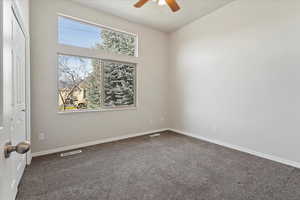 Carpeted spare room with baseboards and ceiling fan