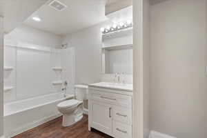 Full bath with dark wood finished floors, vanity, shower / tub combination, a textured ceiling, and recessed lighting