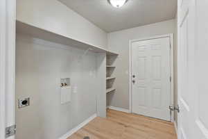 Washroom featuring a textured ceiling, light wood-style floors, hookup for a washing machine, and hookup for an electric dryer