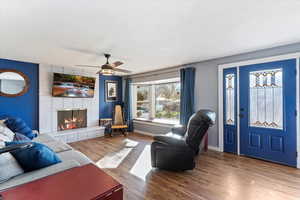 Living area with laminate floors, a fireplace, and ceiling fan