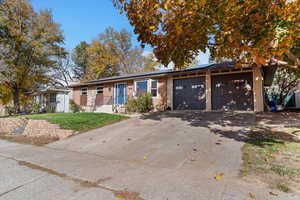 View of front facade featuring driveway, roof mounted solar panels, a garage, a front lawn, and brick siding