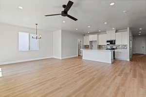 Kitchen featuring open floor plan, white cabinets, decorative backsplash, a ceiling fan, and recessed lighting