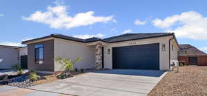 View of front facade with an attached garage, concrete driveway, stucco siding, and a tile roof