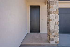 View of exterior entry with stone siding and stucco siding