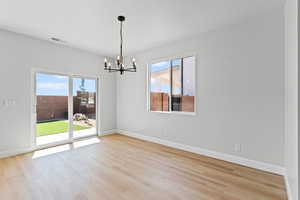 Unfurnished dining area with light wood-style flooring and a chandelier