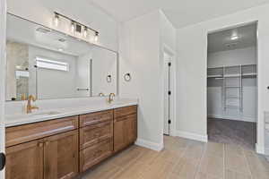 Bathroom featuring a walk in closet, double vanity, a textured ceiling, and a marble finish shower