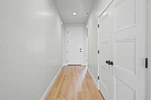Hall with light wood-style flooring and recessed lighting