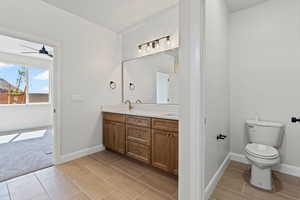 Full bathroom with double vanity, light carpet, and ceiling fan