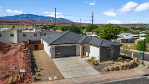 View of front of home featuring a garage, stucco siding, a mountain view, and driveway