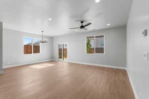 Empty room with recessed lighting, plenty of natural light, light wood-style flooring, a chandelier, and a ceiling fan