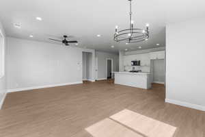 Unfurnished living room with recessed lighting, a chandelier, a ceiling fan, and light wood finished floors