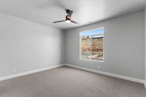 Carpeted empty room with baseboards and a ceiling fan