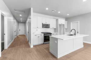 Kitchen with gas range oven, tasteful backsplash, recessed lighting, stainless steel microwave, and white cabinets
