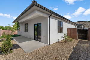 Back of property with a fenced backyard, stucco siding, a gate, and a patio