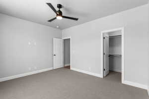 Unfurnished bedroom with light colored carpet, a spacious closet, and ceiling fan