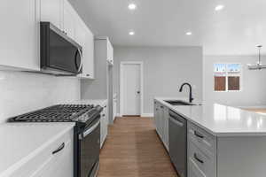 Kitchen featuring appliances with stainless steel finishes, white cabinets, dark wood finished floors, tasteful backsplash, and recessed lighting