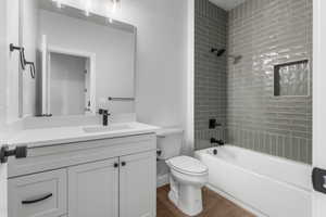 Bathroom with bathtub / shower combination, vanity, and dark wood-style floors