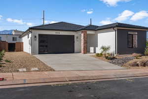 View of front of property with stucco siding, driveway, and an attached garage