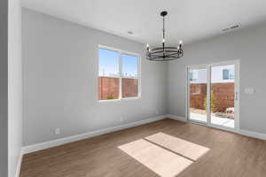 Empty room with a chandelier and light wood finished floors