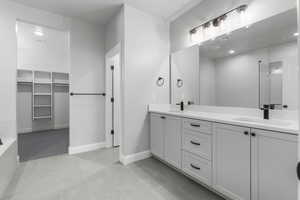 Full bathroom featuring a walk in closet, double vanity, light tile patterned flooring, and a tile shower