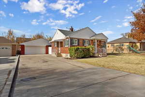 Ranch-style house featuring a garage, an outdoor structure, a front yard, and brick siding