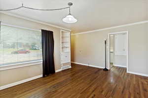 Unfurnished room featuring ornamental molding, dark wood-type flooring, and built in features