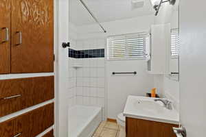 Bathroom with vanity, light tile patterned floors, a textured ceiling, and tub / shower combination