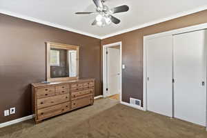 Carpeted bedroom featuring crown molding, a closet, and a ceiling fan